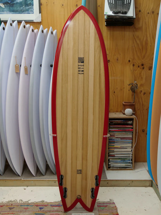 個性を放つSINE SURFの木製ボード。多用途なクアッドフィンと目を引く赤のレールが、あなたのライディングを彩る。