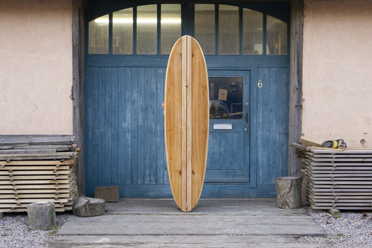 次のオーナーを待つかのような、堂々とした佇まいの中空構造(ホロー)の木製サーフボード(天然木)。クラシックなロングボードの風格と、現代的な技術が融合した大人のサーフスタイル。