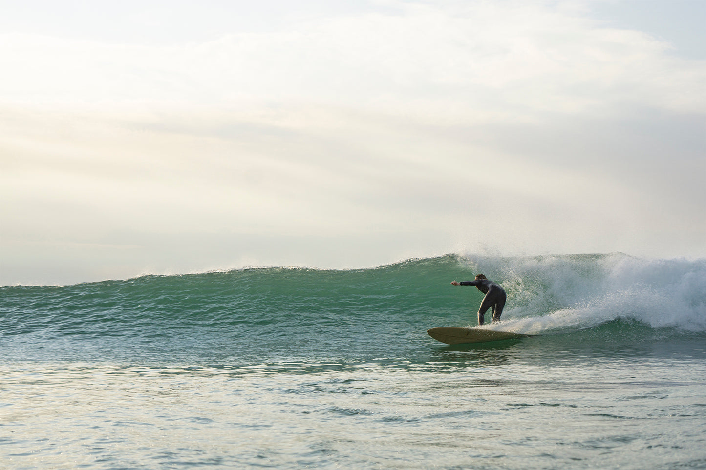 完璧に整ったグラス面なうねりを、中空構造(ホロー)の木製サーフボード(天然木)でスタイリッシュにカービング。メローな光とスプレーが交錯する、サーファーなら誰もが憧れる至福のセッション。