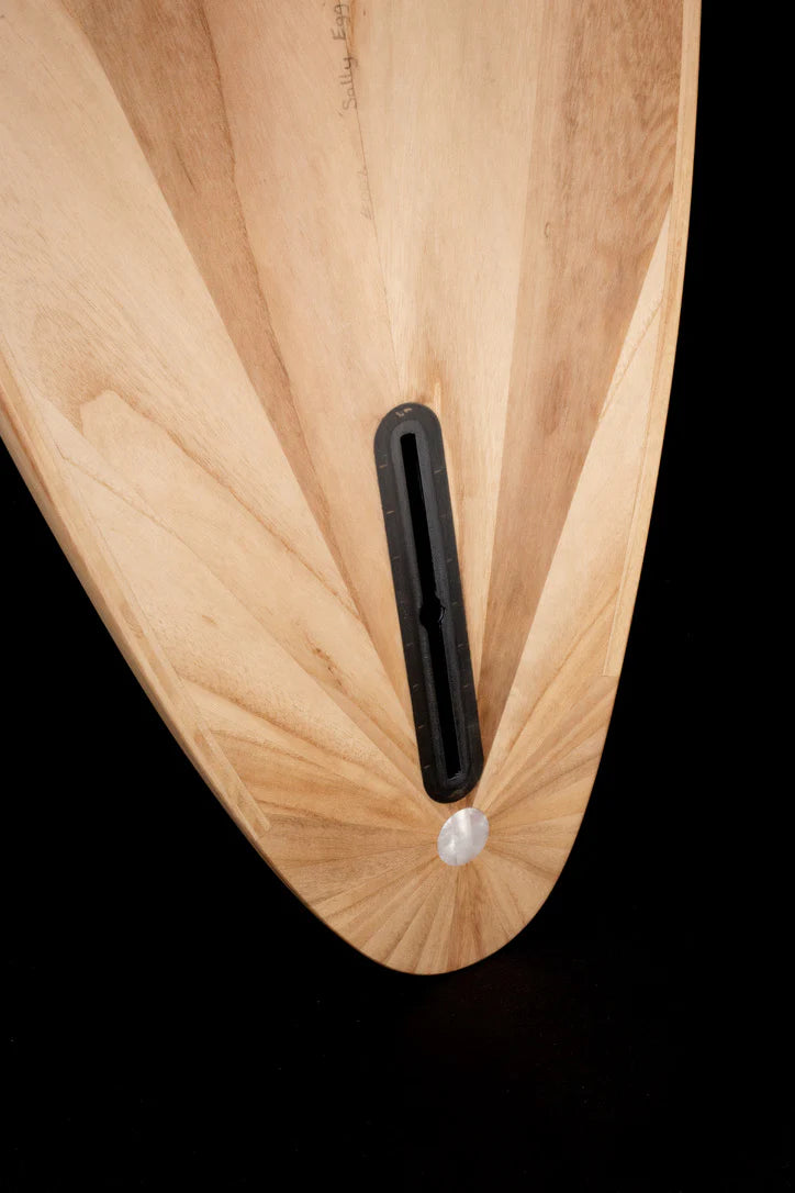 中空構造（ホロー）の木製サーフボード（天然木）のラウンドテール詳細。美しい放射状の木目（サンバースト）とシングルフィンボックス、職人技が宿る洗練されたエコラグジュアリーなデザイン。