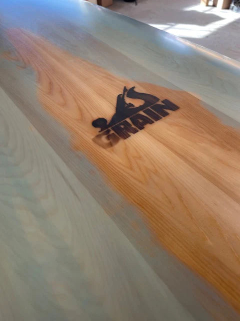 Grain Surfboardsの焼印ロゴと美しい木目。ブルーティントに浮かび上がる職人技の証。