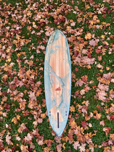 紅葉に囲まれた芝生の上に置かれた7'4" Ternサーフボード。木目とブルーグリーンのマーブル模様が美しく調和したデザイン。