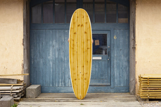 中空構造（ホロー）の木製サーフボード（天然木）を支える職人の手。丁寧な手仕事によって生まれた一点物の存在感、インテリアとしても映える上質なウッドデザイン。