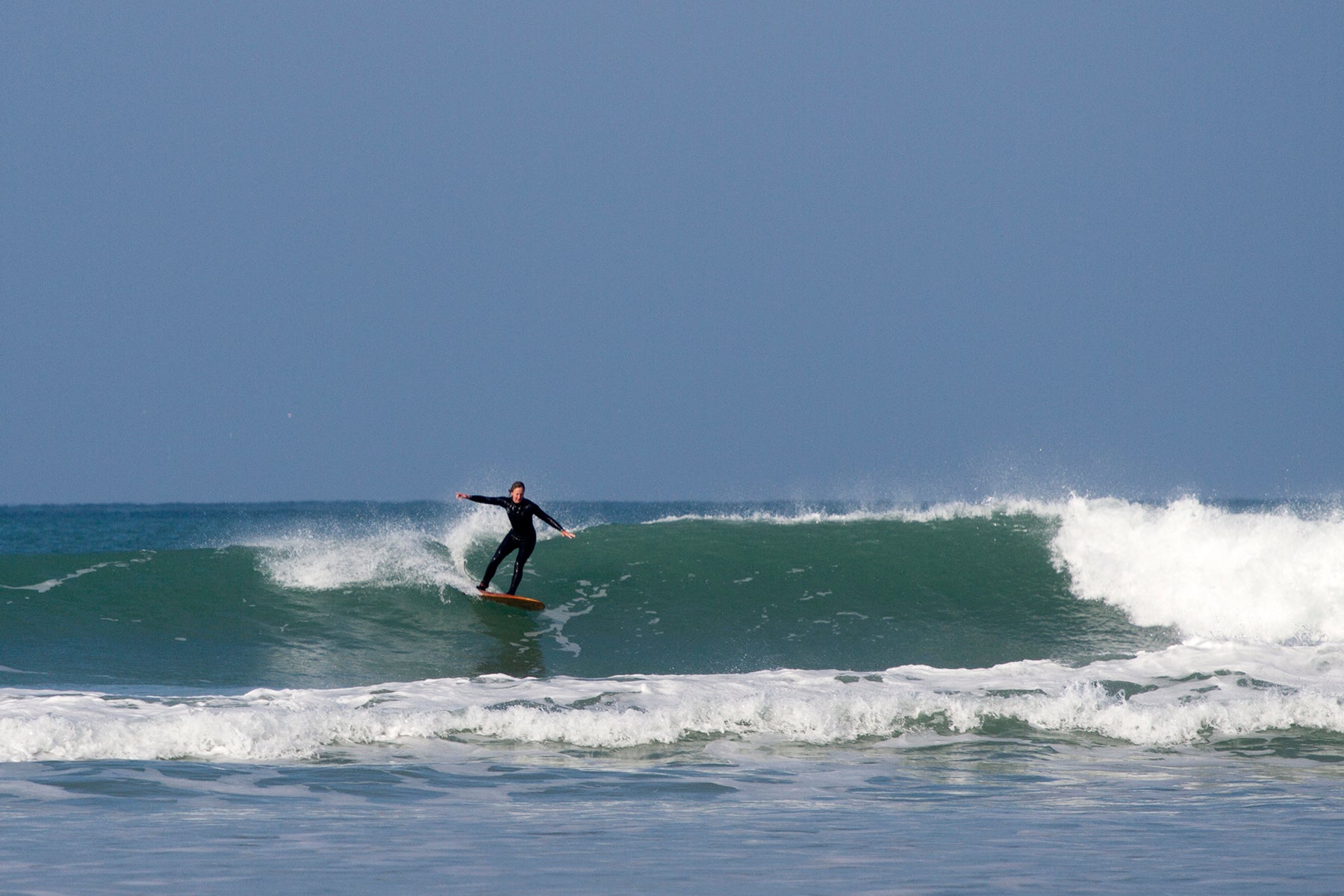 完璧なコンディションに恵まれた休日の一コマ。中空構造（ホロー）の木製サーフボード（天然木）と共に波のリズムに乗る、開放感と喜びに満ちた大人のサーフライフスタイル。