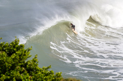 セットの波を捉え、中空構造（ホロー）の木製サーフボード（天然木）で急斜面を滑り降りる瞬間。クリフサイドから見下ろす臨場感あふれるライン取り、アドレナリンが湧き出る至高のライディング。