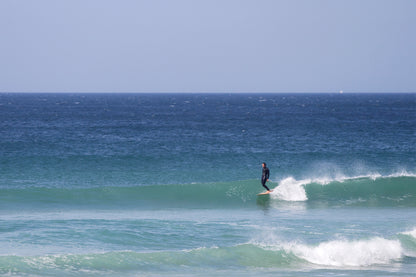 穏やかな晴天の海、セットの波をキャッチして優雅にクルージング。中空構造（ホロー）の木製サーフボード（天然木）ならではの伸びやかなグライド感と、リラックスした大人のサーフシーン。