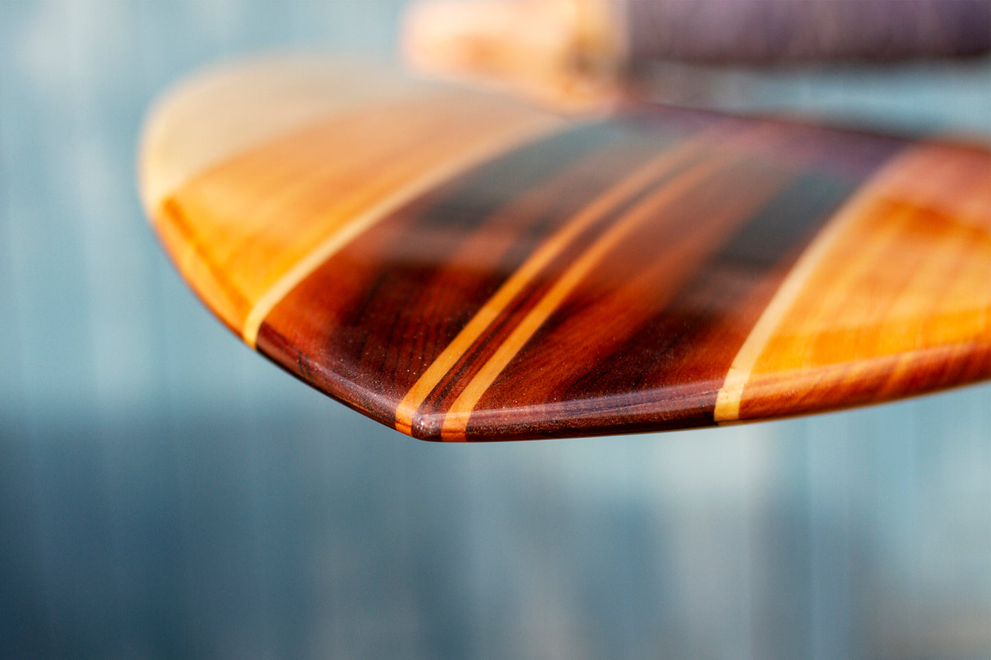 飴色に輝くシダー（杉）やポプラなどの木材が織りなす、深みのあるグラデーション。ガラスのように滑らかなレジンコーティングの下に透ける緻密な木目が、飾れる・乗れるサステナブルな機能美と、天然素材だけが持つ温かな質感を伝えている。