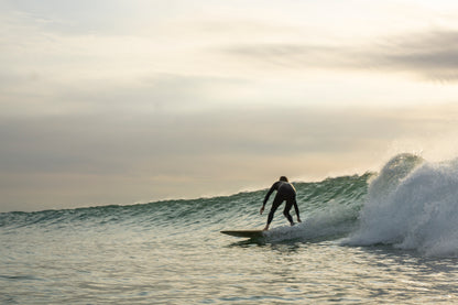 サンセットタイムのグラッシーな波で、中空構造（ホロー）の木製サーフボード（天然木）をトリミング。一日の終わりを締めくくる至福のライディングと、心に残る美しい光景。