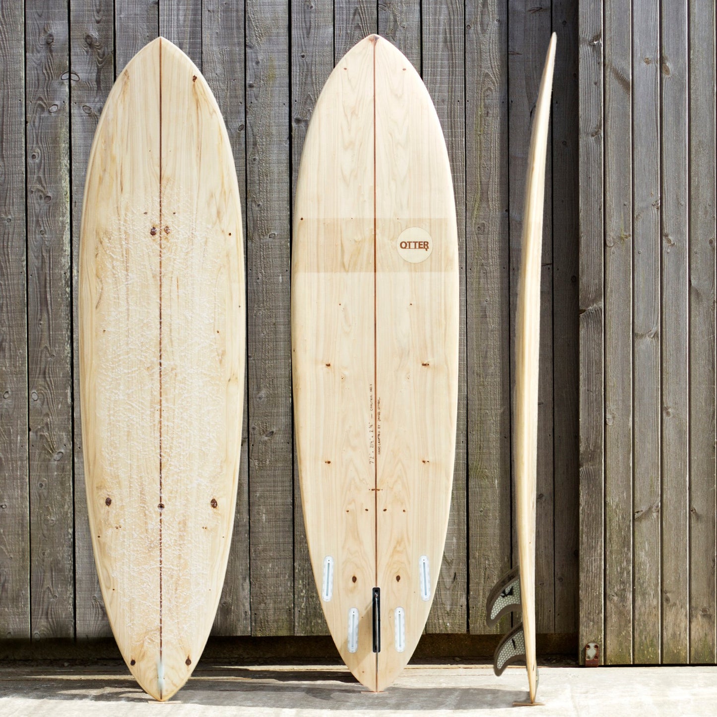 中空構造（ホロー）の木製サーフボード（天然木）に見る、ワックスアップされたデッキとスムースなボトムの質感。背景のグレーの古材が引き立てるナチュラルな素材感、飾れる・乗れるサステナブルな機能美。