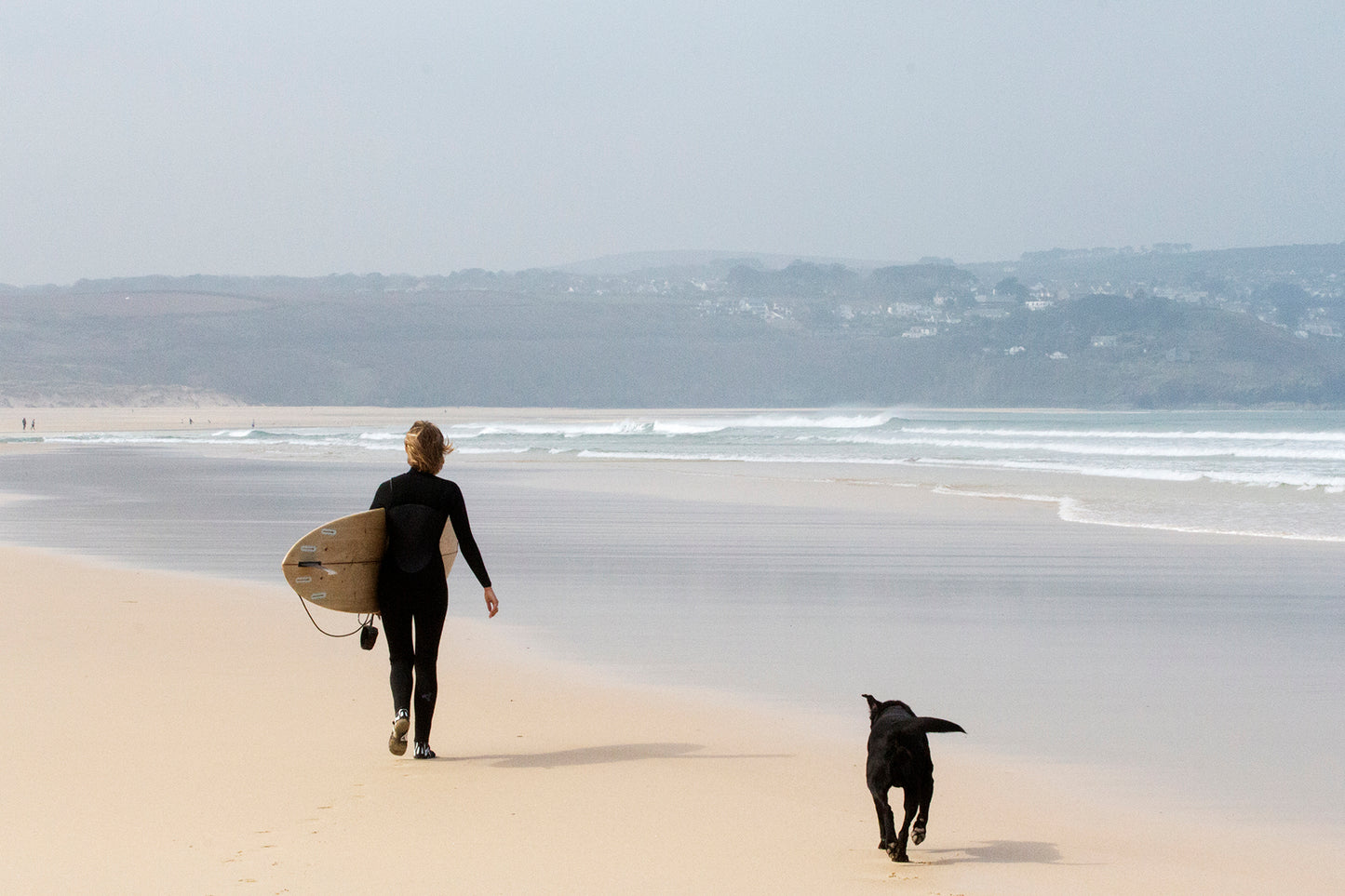オフショアに整えられた小波のラインを見つめ、中空構造（ホロー）の木製サーフボード（天然木）と共にビーチを歩く。愛犬とシェアするメローな朝のセッション、心身をリセットする贅沢な週末。