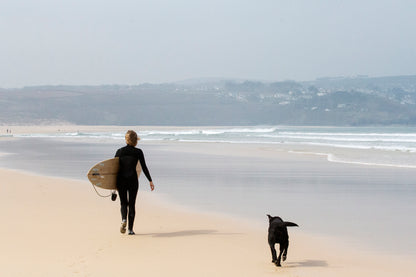 オフショアに整えられた小波のラインを見つめ、中空構造（ホロー）の木製サーフボード（天然木）と共にビーチを歩く。愛犬とシェアするメローな朝のセッション、心身をリセットする贅沢な週末。