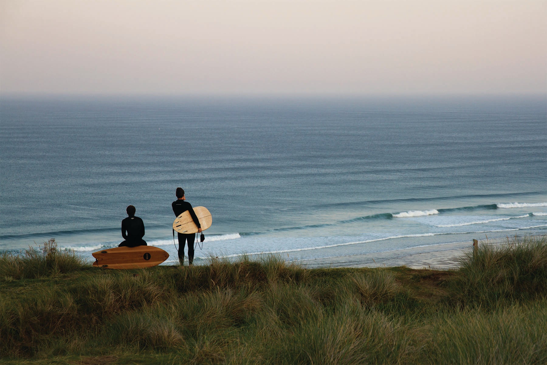 整ったうねりのラインを丘の上からチェックするサーファーたち。中空構造（ホロー）の木製サーフボード（天然木）と共に、ベストな潮周りを待つ期待に満ちたサーフチェックの風景。