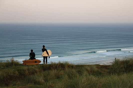 整ったうねりのラインを丘の上からチェックするサーファーたち。中空構造（ホロー）の木製サーフボード（天然木）と共に、ベストな潮周りを待つ期待に満ちたサーフチェックの風景。